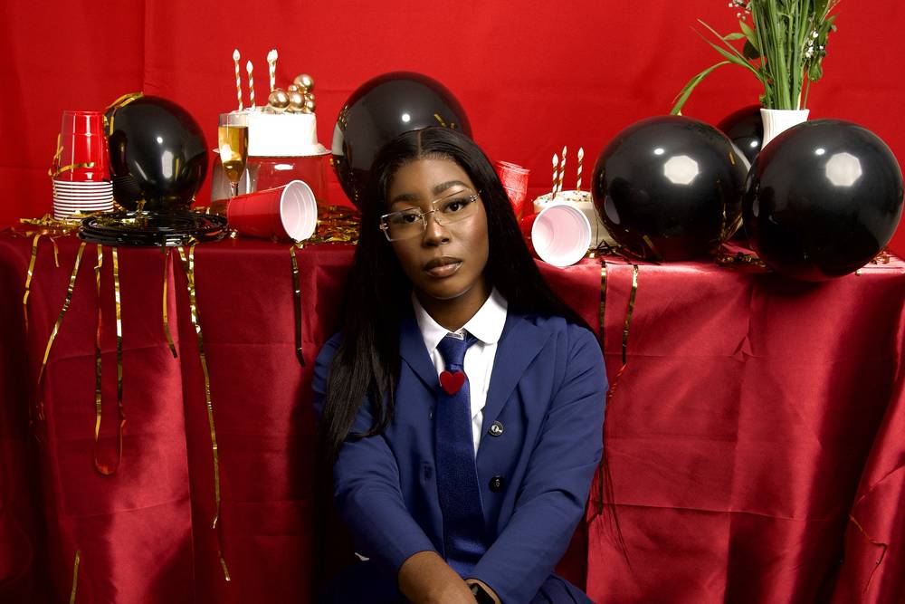 Studio portrait on a red set with black balloons